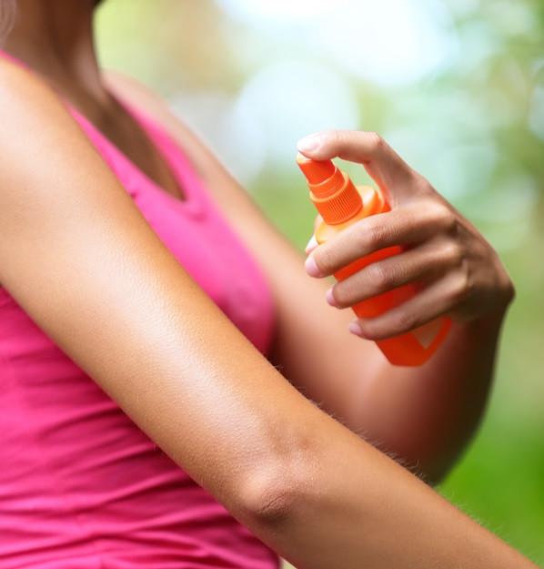 Mosquito repellent. Woman spraying insect repellents on skin out